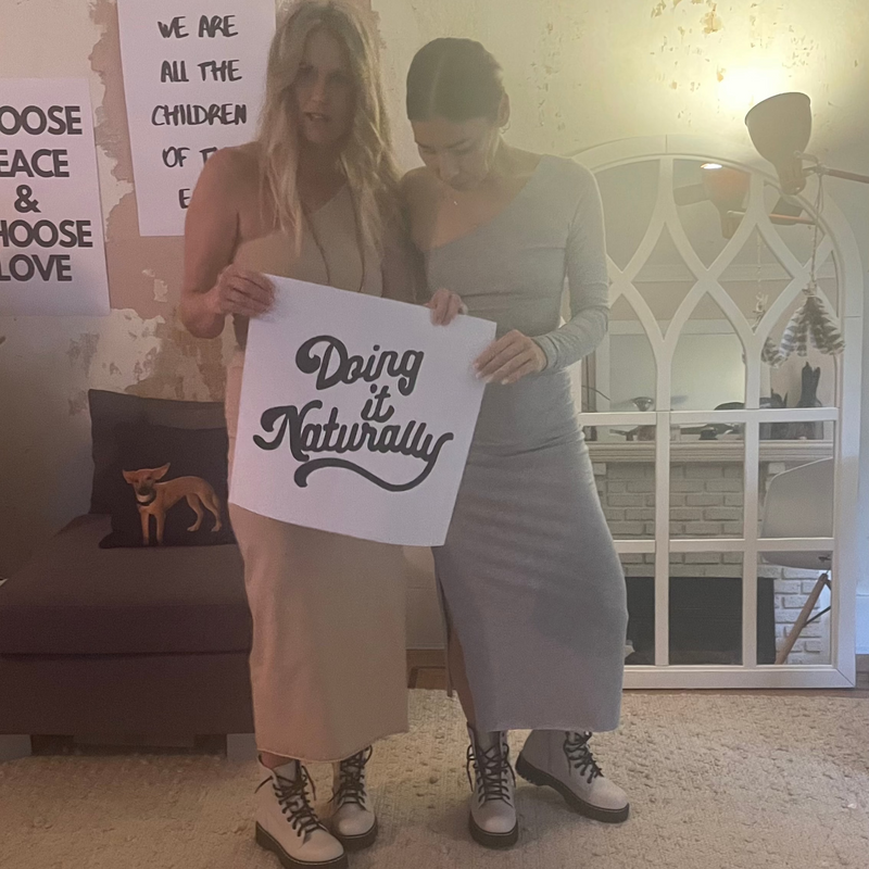 natural fiber ~ 2 women wearing matching outfits carrying Doing it Naturally sign
